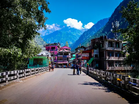 Village road crossing with brightly painted buildings beneath mountains.