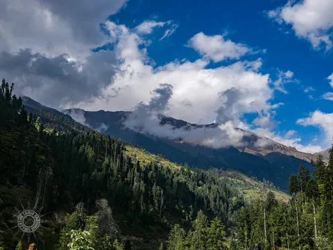 Layered mountain ridges and clouds above a Wailing cannabis field.