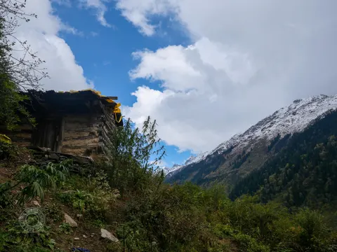 Snow-streaked mountain valley beside a wooden building.