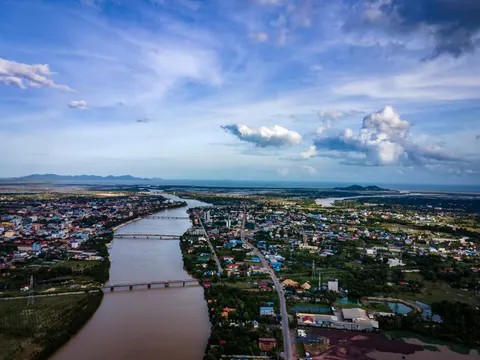 A coastal town along a wide brown river, two bridges crossing it and the sea beyond, seen from the air.