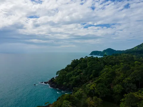 Forested Koh Chang coastline and distant islands beneath broken cloud.