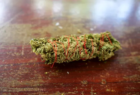 Side view of a locally produced Koh Chang Buddha stick tied with red thread.