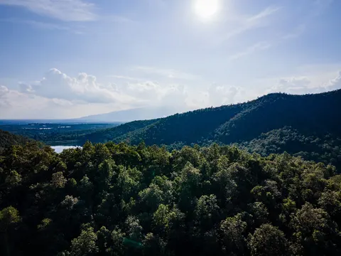 The same hills and lake seen into the sun, ridges falling away to the plain.